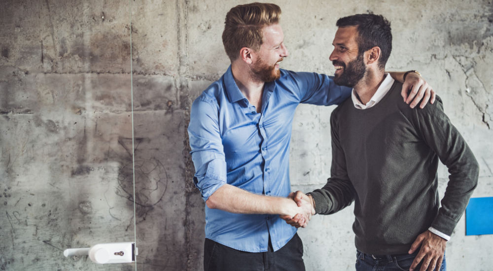 Two young, casually dressed men shaking hands